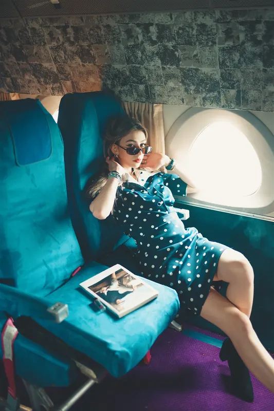 Anaïs en robe à pois sur un siège turquoise de cabine