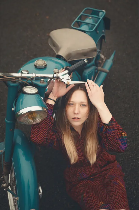 Kessy contre une moto ancienne bleu canard