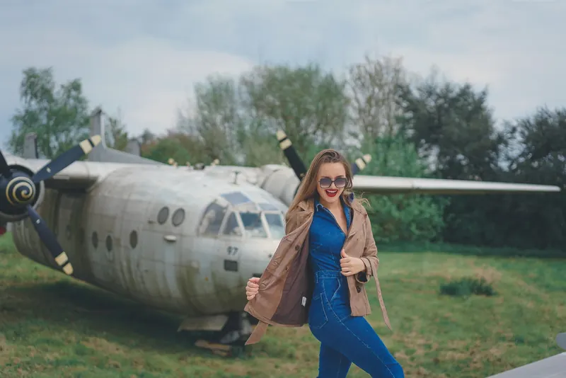 Paola en trench devant un avion à hélices
