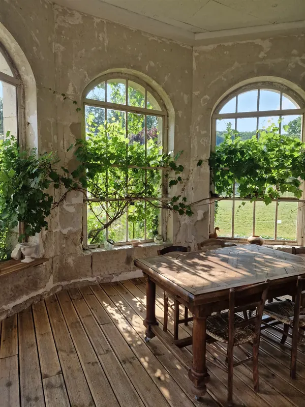 La véranda du gîte, ses grandes fenêtres cintrées et la vigne