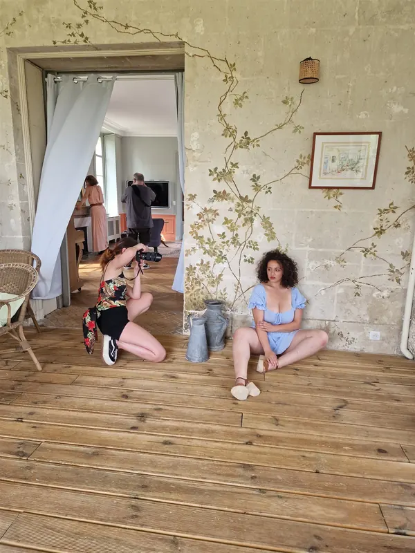 Deux modèles assises sur le parquet dans une pièce aux murs peints
