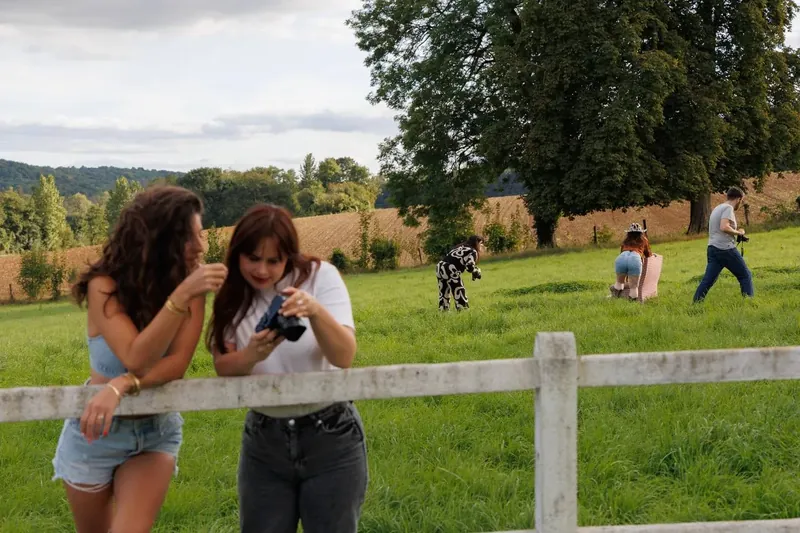 Deux participantes regardent leurs photos au téléphone pendant que le groupe shoote dans le pré