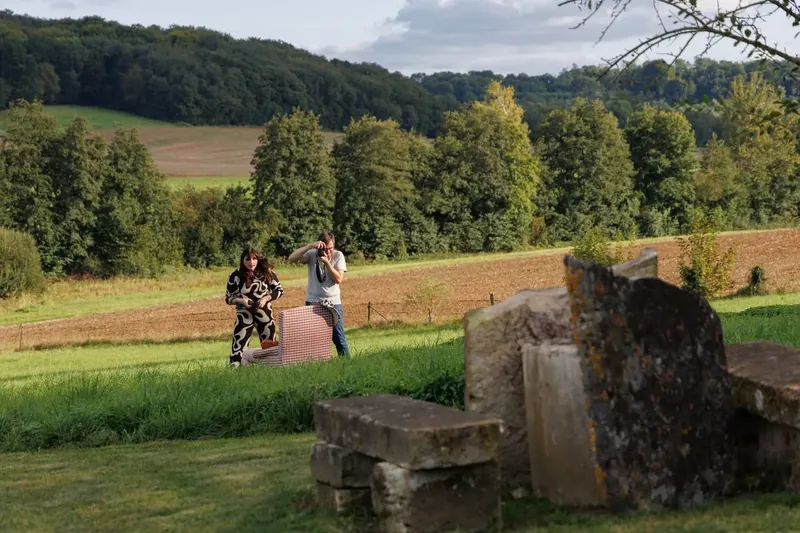 Le parc du gîte : un duo photographe et modèle au fond de la prairie, la forêt derrière