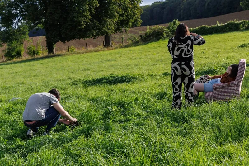 La même scène vue de loin : un photographe accroupi dans les hautes herbes