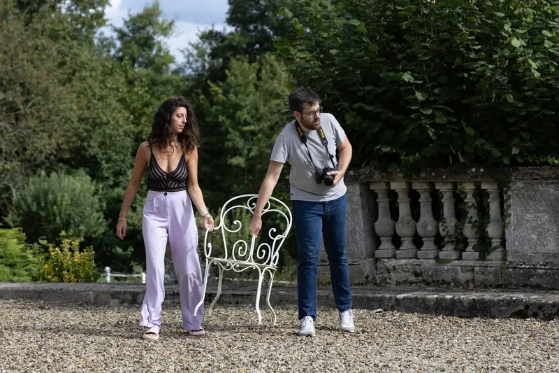 Un photographe et une modèle sur le perron en gravier, près de la balustrade