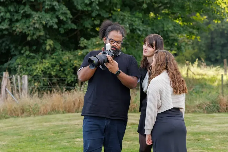 Un photographe vérifie son cadrage, deux participantes juste à côté