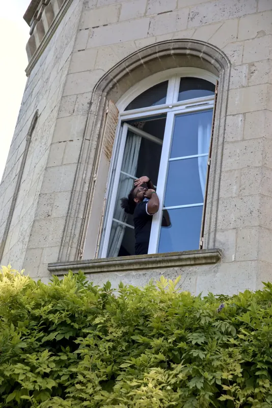 Un photographe shoote depuis une fenêtre cintrée de l’étage