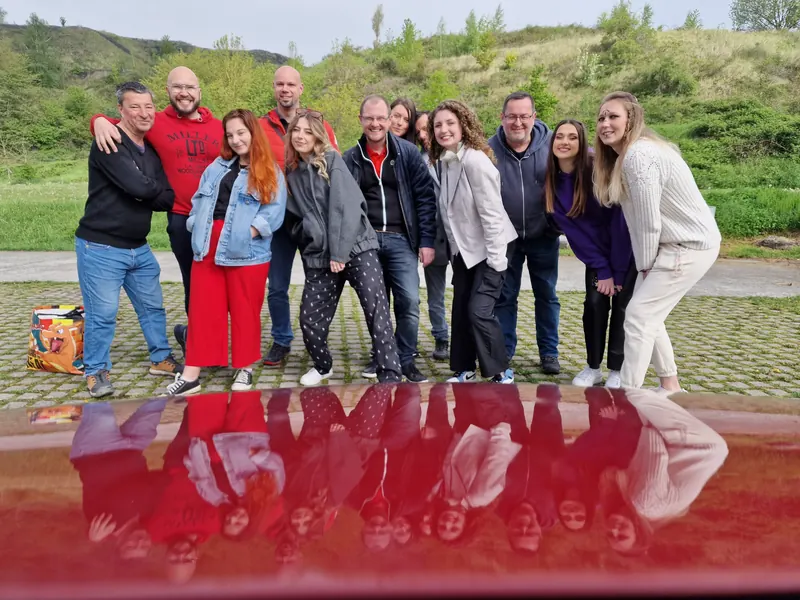 Photo de groupe de la sortie photo sur le parking des terrils, reflet sur le capot d’une voiture rouge